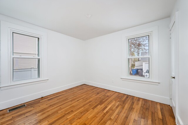 unfurnished room with light wood-type flooring, visible vents, and baseboards