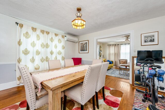 dining room with hardwood / wood-style flooring, baseboards, and a wall mounted AC