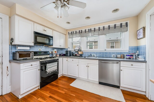 kitchen featuring dark countertops, a sink, black appliances, and ceiling fan