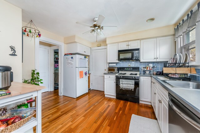 kitchen with black appliances, ceiling fan, wood finished floors, and white cabinets