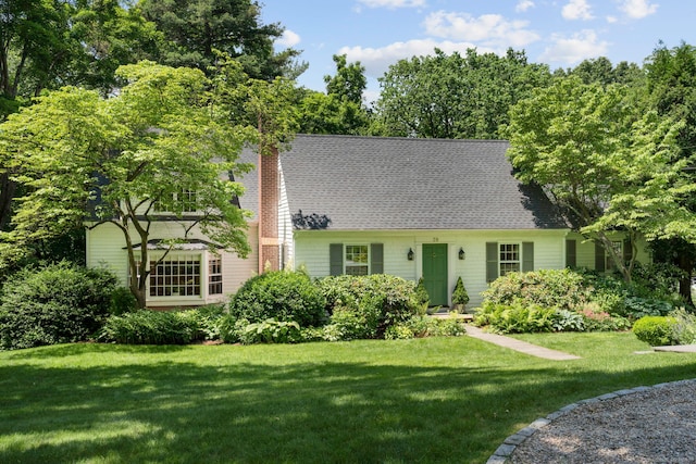 new england style home with a front lawn and roof with shingles