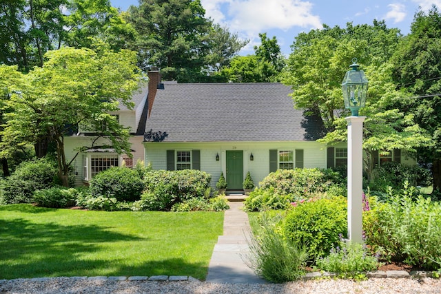 view of front of house featuring a chimney, a shingled roof, and a front lawn