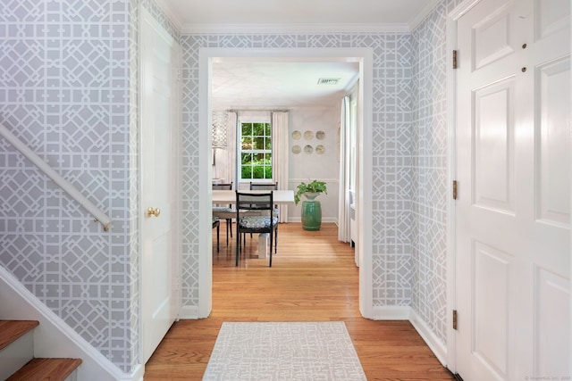 corridor featuring ornamental molding, visible vents, baseboards, and light wood-type flooring