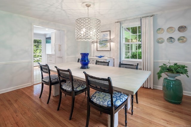 dining space featuring an inviting chandelier, crown molding, and light wood-style flooring
