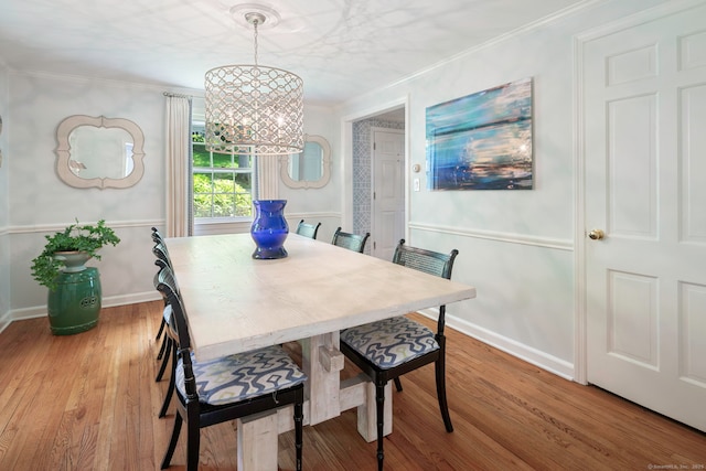 dining area featuring ornamental molding, an inviting chandelier, baseboards, and light wood-style floors