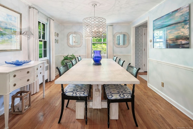 dining space with baseboards, a notable chandelier, crown molding, and light wood-style flooring