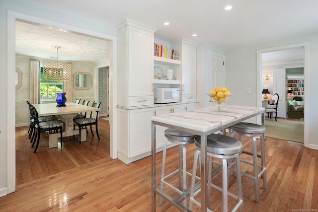kitchen featuring a chandelier, white cabinets, white microwave, and light wood finished floors