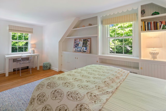 bedroom featuring radiator heating unit, wood finished floors, and baseboards