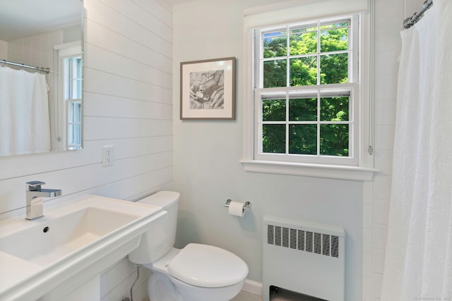 full bathroom featuring curtained shower, radiator, toilet, and a sink
