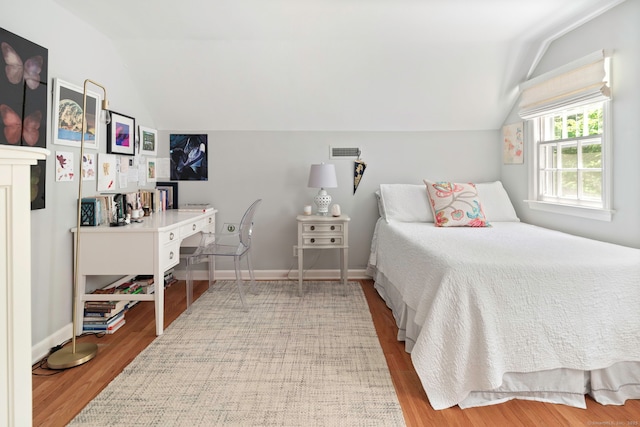 bedroom with wood finished floors, visible vents, vaulted ceiling, and baseboards
