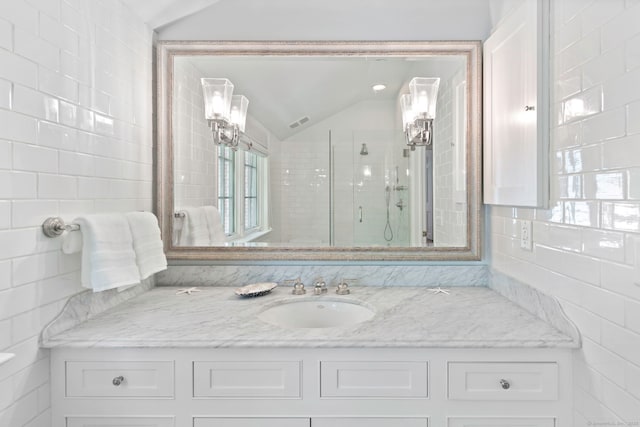 full bathroom featuring vanity, tile walls, a shower stall, and lofted ceiling