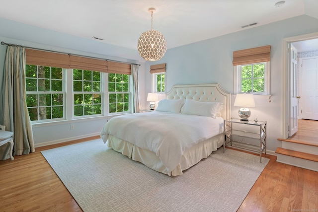 bedroom with baseboards, visible vents, and wood finished floors