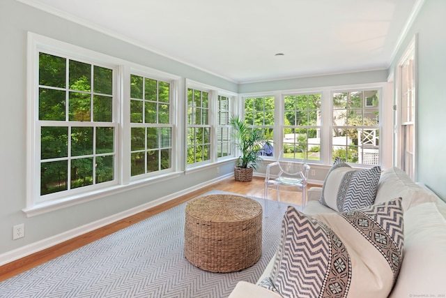 sunroom / solarium featuring baseboards, wood finished floors, and crown molding