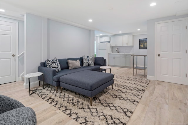 living area featuring baseboards, recessed lighting, and light wood-type flooring