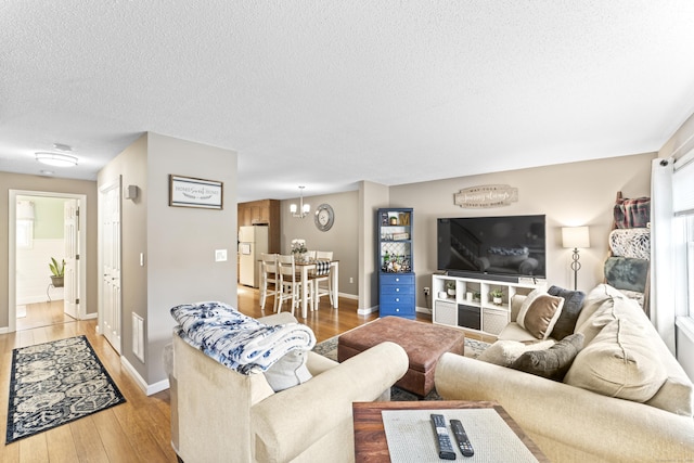 living area featuring baseboards, a textured ceiling, and light wood-style flooring