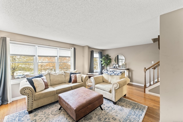 living room featuring baseboards, stairway, wood finished floors, and a textured ceiling