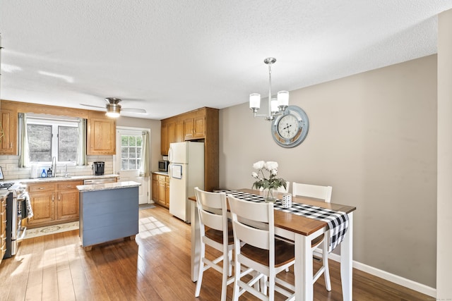 kitchen featuring light wood-style flooring, appliances with stainless steel finishes, a kitchen island, backsplash, and a textured ceiling