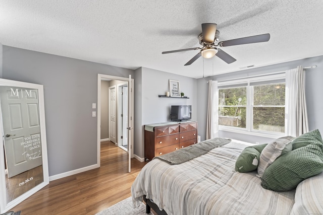bedroom with baseboards, wood finished floors, a ceiling fan, and a textured ceiling