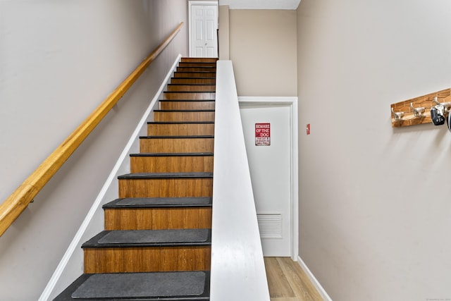 staircase featuring baseboards and wood finished floors