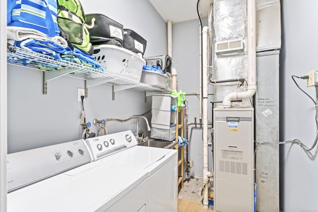 laundry room with light wood-style floors, washer and clothes dryer, heating unit, and laundry area