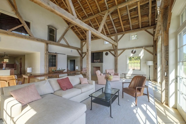 living area featuring beamed ceiling, high vaulted ceiling, a barn door, and carpet floors