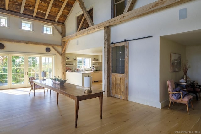 dining space featuring a barn door, high vaulted ceiling, light wood-style flooring, wood ceiling, and french doors