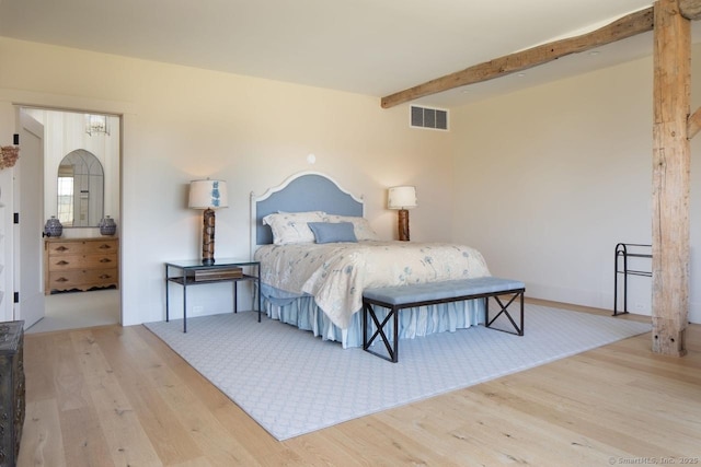 bedroom featuring visible vents, wood finished floors, and beamed ceiling