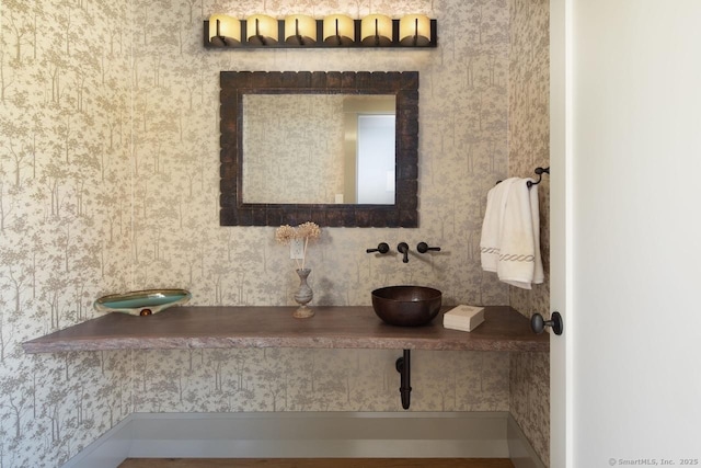 bathroom with wallpapered walls and a sink