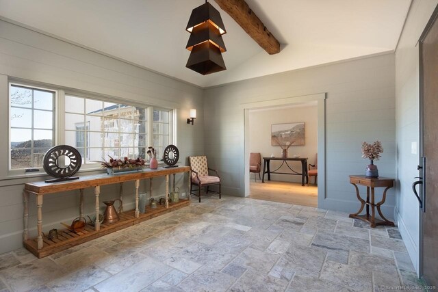 sitting room with lofted ceiling with beams and stone tile floors