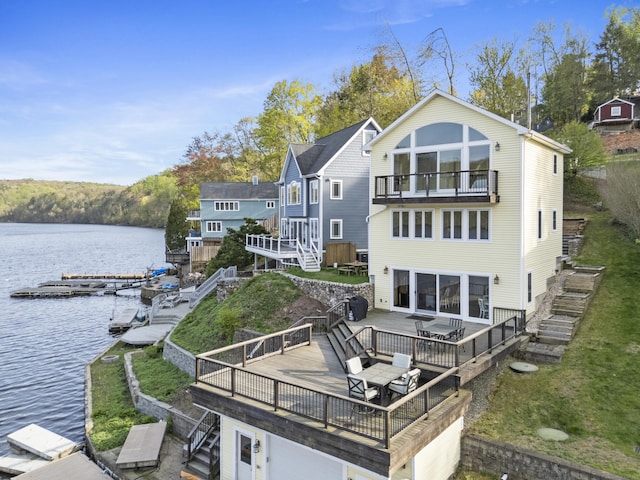 back of house with a deck with water view, stairway, and a balcony