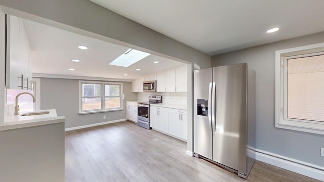 8 Batt St, Middletown, CT 06457 - kitchen with a skylight, appliances with stainless steel finishes, light wood finished floors, a sink, and white cabinetry