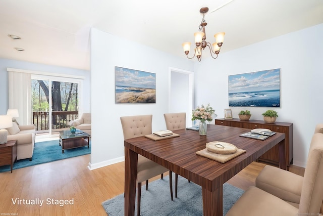 dining space featuring light wood-type flooring, a notable chandelier, and baseboards