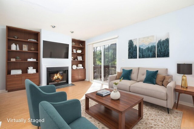 living room with a fireplace with flush hearth, light wood-style flooring, and baseboards