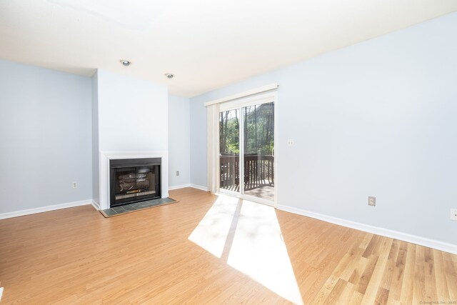 unfurnished living room featuring a fireplace, light wood-style floors, and baseboards