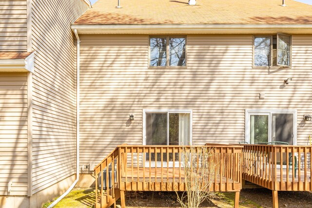 rear view of property with a shingled roof and a wooden deck
