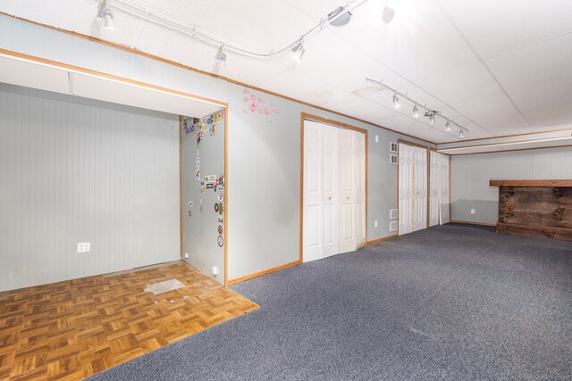 finished below grade area with rail lighting, wooden walls, and baseboards