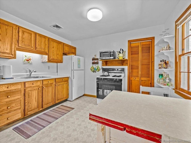 kitchen with a sink, white appliances, open shelves, visible vents, and light countertops