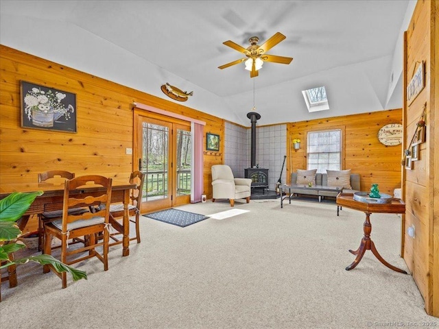 living area with carpet, a wood stove, and lofted ceiling with skylight