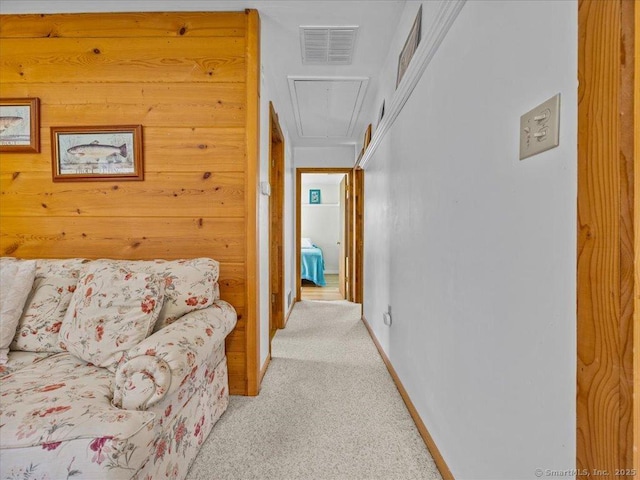 hallway featuring baseboards, visible vents, attic access, and light colored carpet