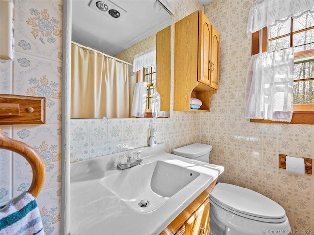 full bath with curtained shower, toilet, wallpapered walls, and vanity