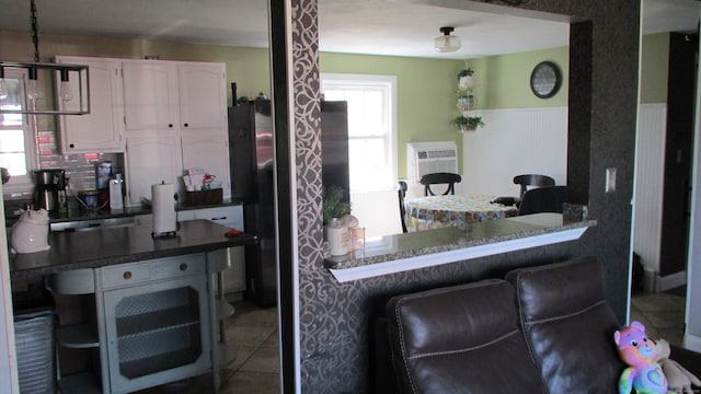 219 Forest St, East Hartford, CT 06118 - kitchen featuring white cabinetry, a kitchen breakfast bar, tile patterned floors, and dark countertops