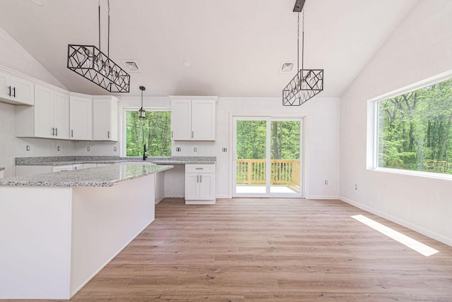 180 Tripp Hollow Rd, Brooklyn, CT 06234 - kitchen featuring vaulted ceiling, white cabinetry, plenty of natural light, and light stone countertops