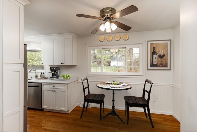 dining space featuring visible vents, a ceiling fan, light wood finished floors, and a wainscoted wall