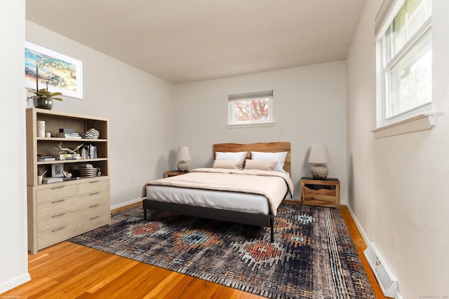 bedroom with baseboards, multiple windows, and wood finished floors