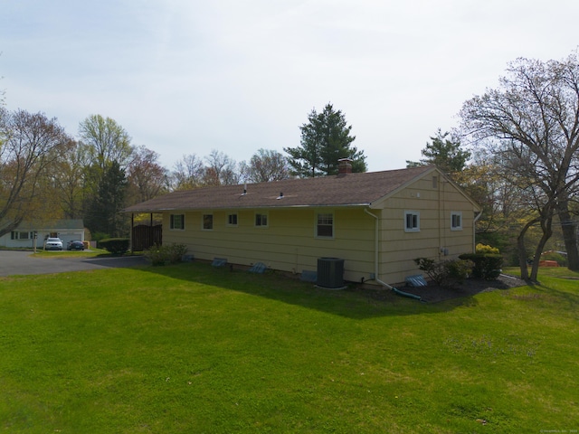 view of home's exterior with a lawn, cooling unit, and a chimney