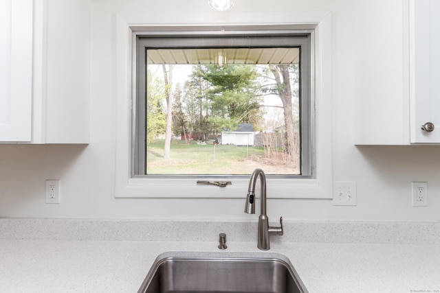 room details with a sink, white cabinets, and light countertops