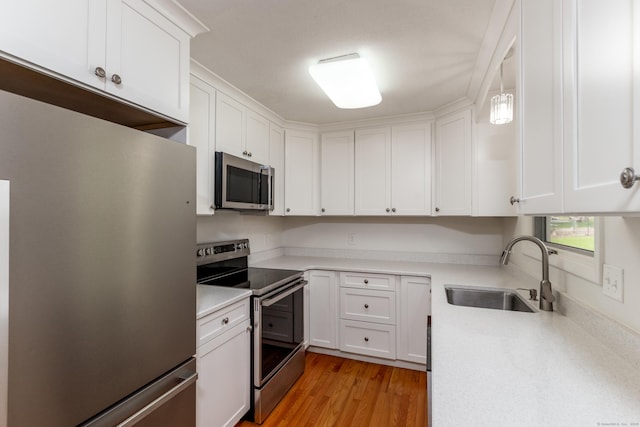 kitchen featuring a sink, light countertops, stainless steel appliances, and white cabinetry