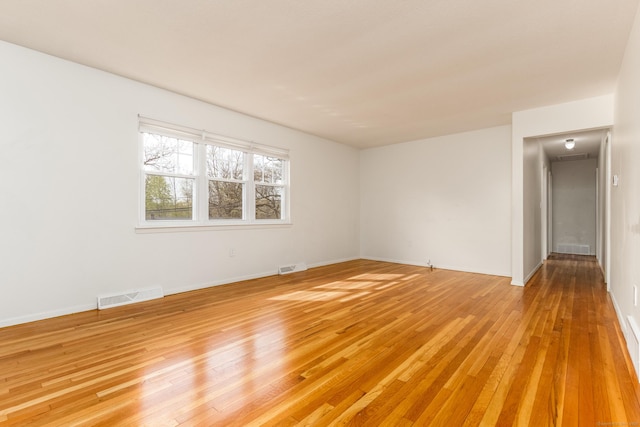 spare room featuring baseboards, visible vents, and light wood-style flooring