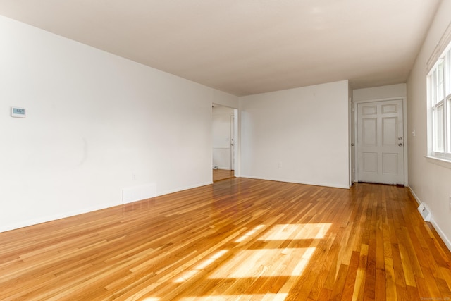unfurnished room featuring light wood-style floors, baseboards, and visible vents