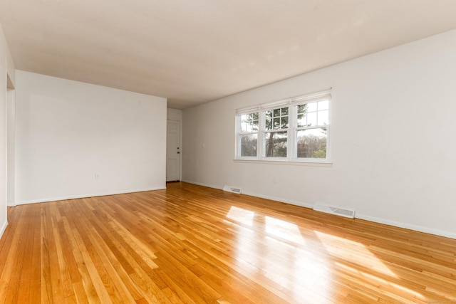 spare room featuring light wood-style floors, baseboards, and visible vents